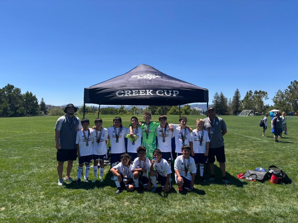 EC Revolution U11 Boys Blue with their Creek Cup finalist medals under the Creek Cup tent
